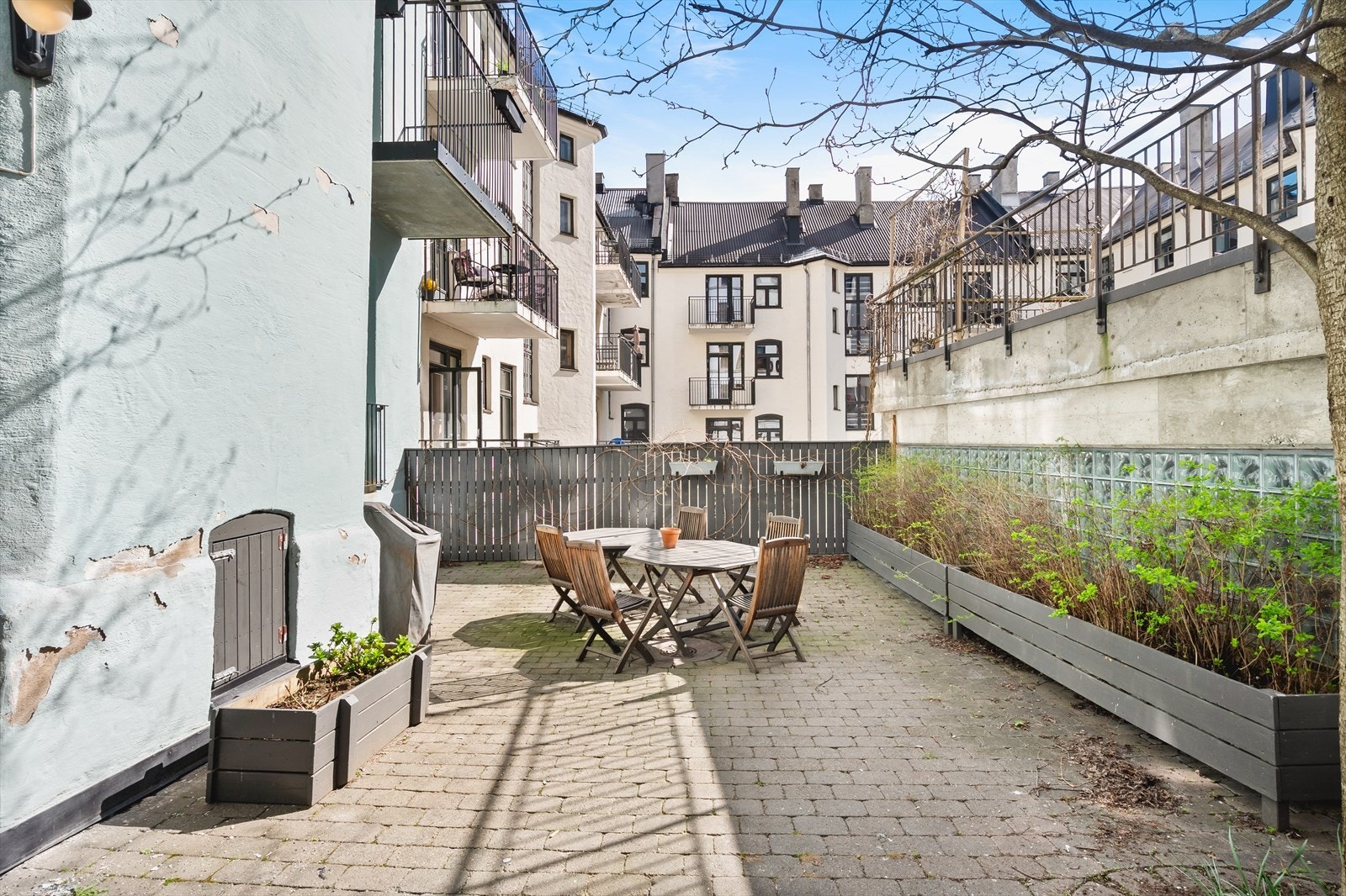 Hyggelig, brosteinsbelagt bakgård med sittegruppe og beplantning. Galleribilde