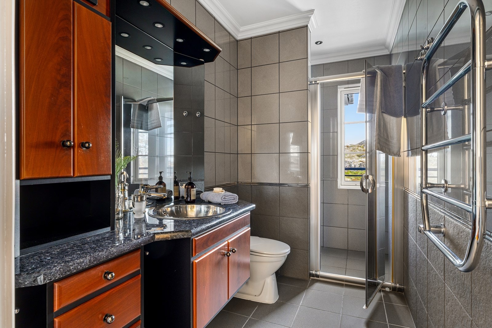 Det andre badet i hovedsuiten har dusjnisje med sjøutsikt og fliser i dempede gråtoner. Galleribilde