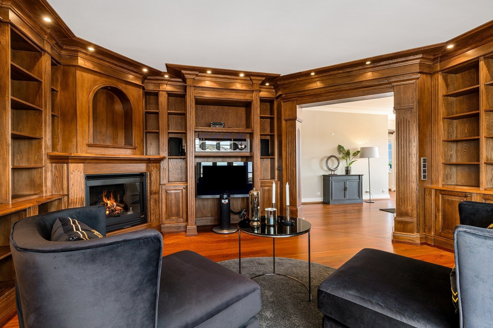 Hele rommet har vegger kledd i heltre med bokhyller, skuffer, brede lister og downlights. Galleribilde