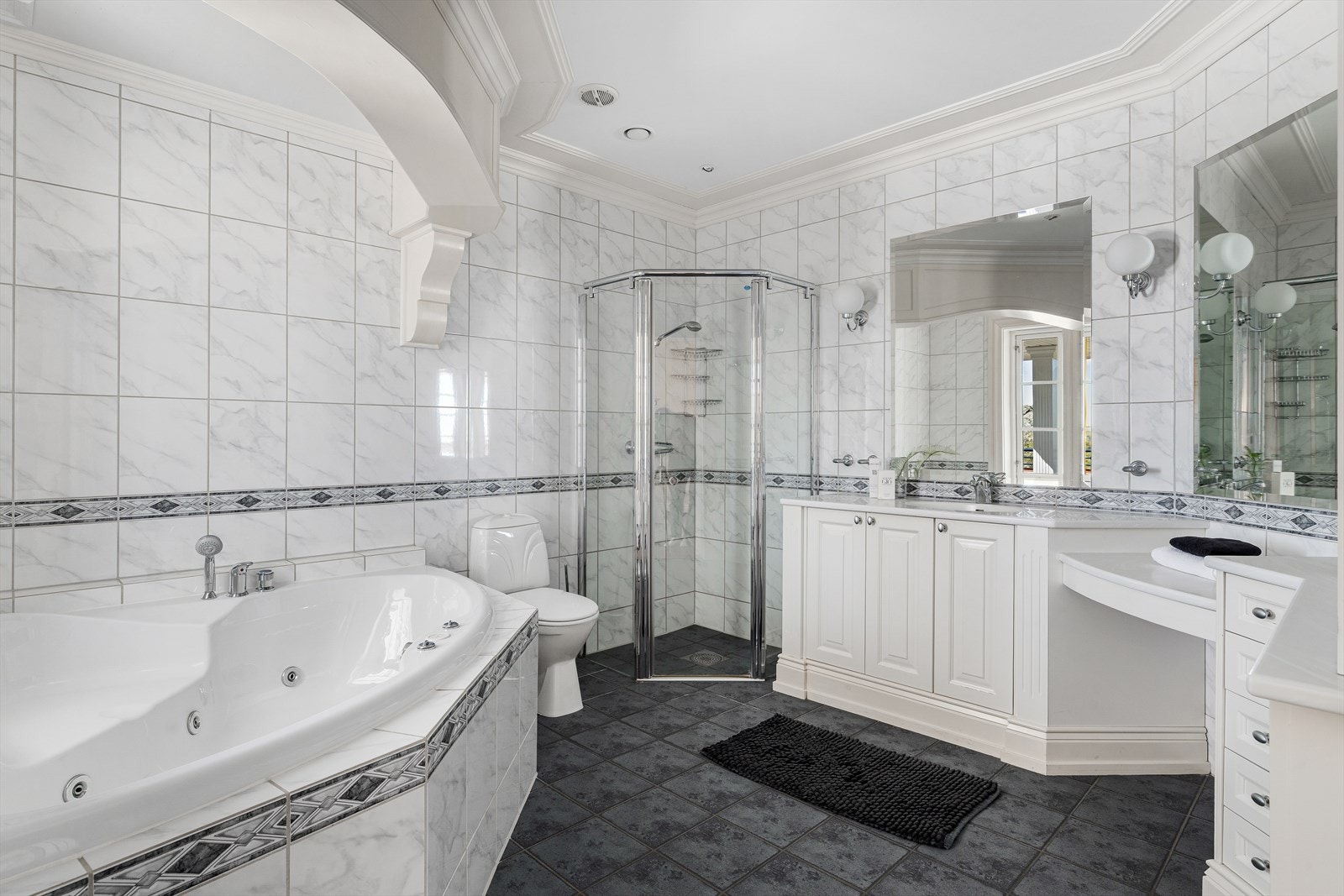 Det største badet i hovedsuiten har både boblebad, dusjhjørne, toalett og rikelig med skapplass. Galleribilde