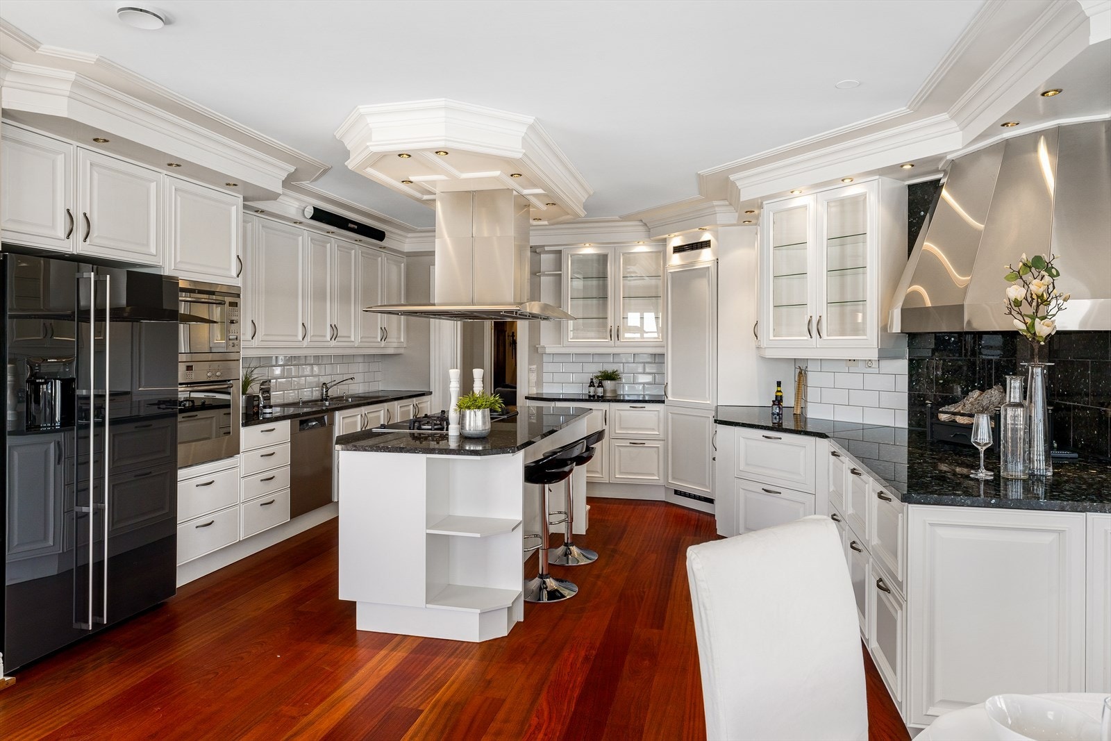 Kjøkkenet er herskapelig med nymalte, hvite fronter, vitrineskap, kjøkkenøy og benkeplater i sort larvikitt. Galleribilde