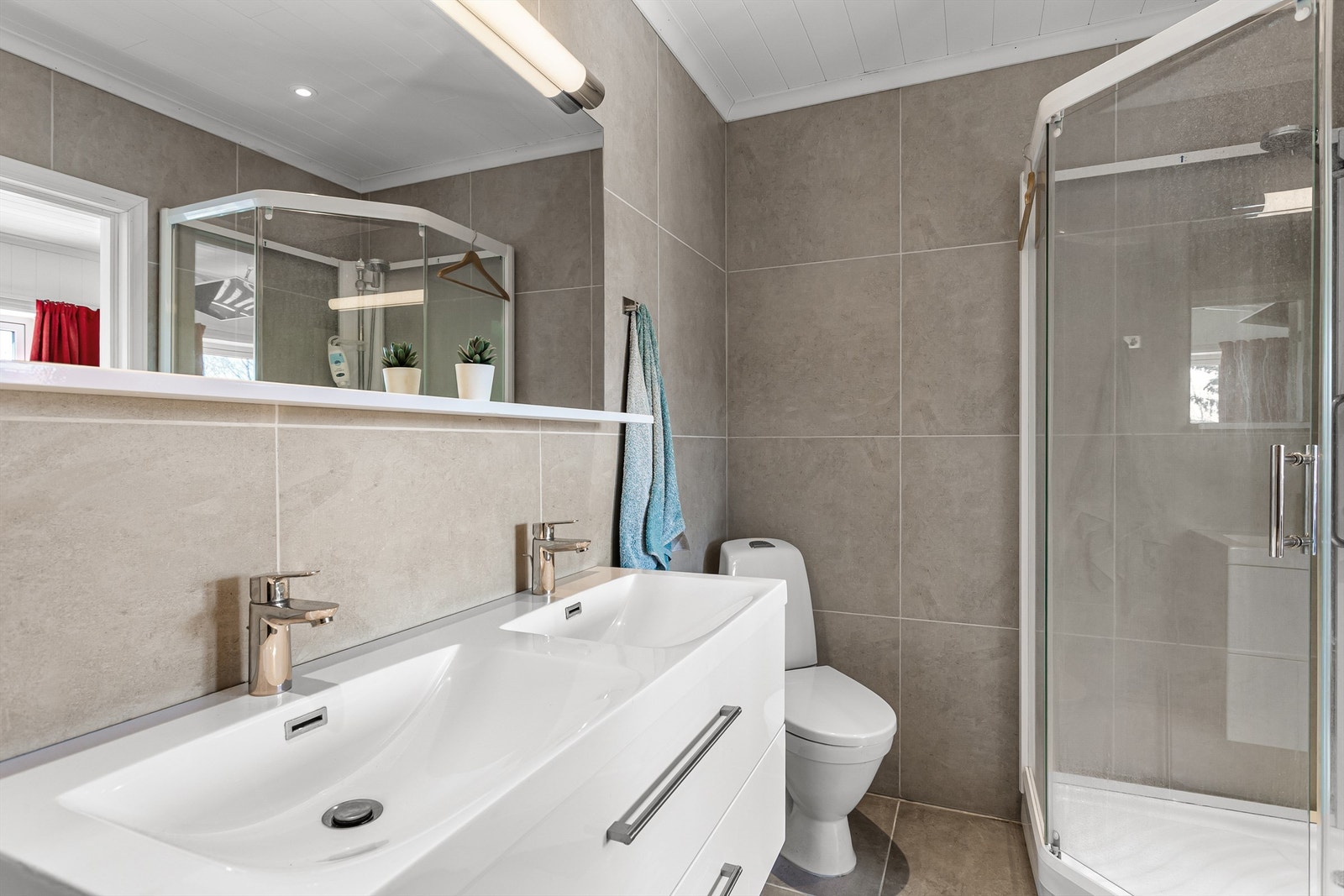 Badet har heldekkende dobbelservant, gulvstående toalett og dusjkabinett Galleribilde