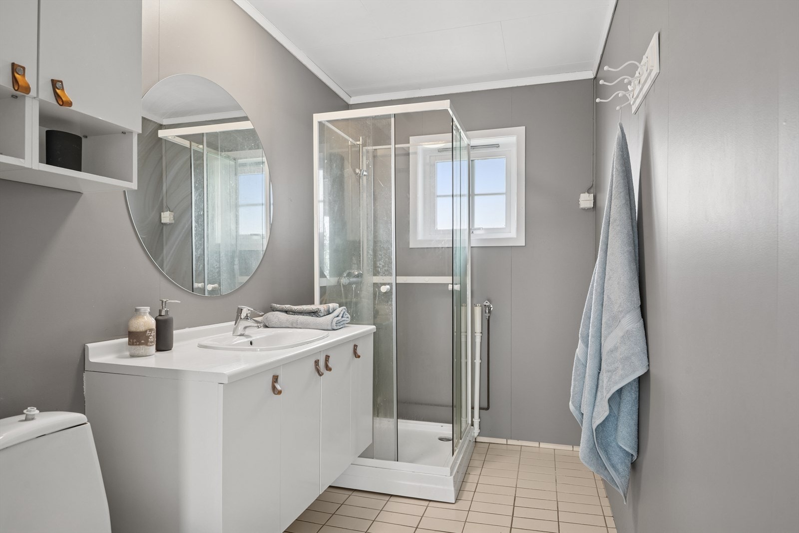 Bad med flislagt gulv, baderomsplater på veggene og dusjkabinett. Galleribilde