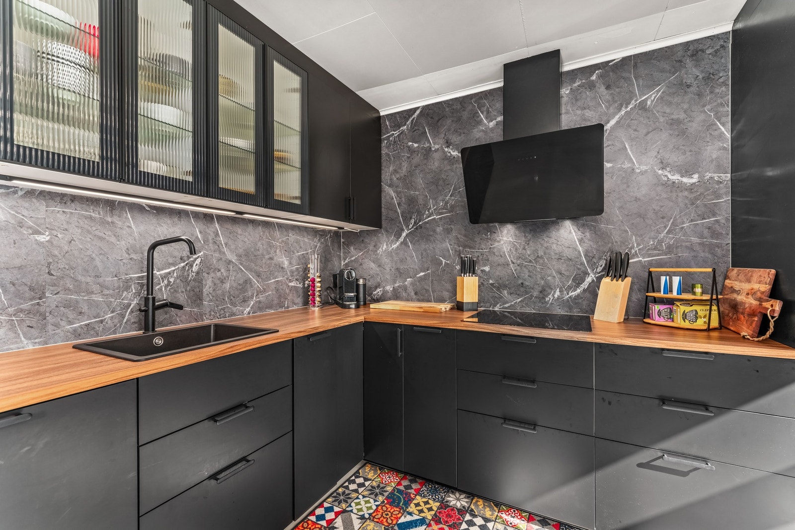 Innredning i slette, sorte fronter og benkeplate i tre med nedfelt kum. Galleribilde