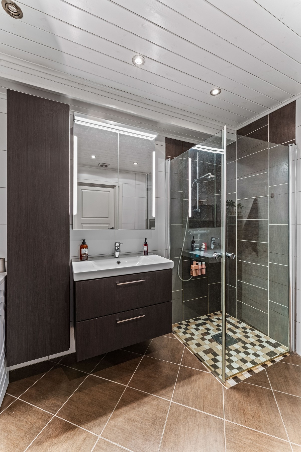 Pen baderomsinnredning med servant og praktisk skuffeløsning under, samt et høyskap som gir godt med oppbevaringsplass. Galleribilde