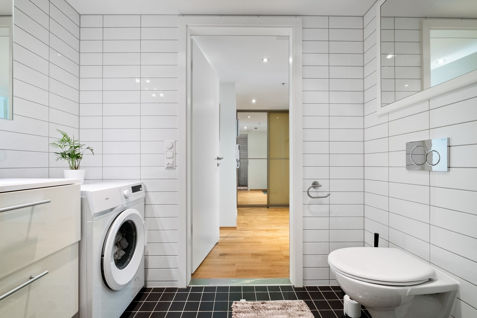 Rommet har servant med slette fronter, veggmontert toalett, dusjvegger/hjørne med to stk svingbare glassdører og opplegg for vaskemaskin. Galleribilde