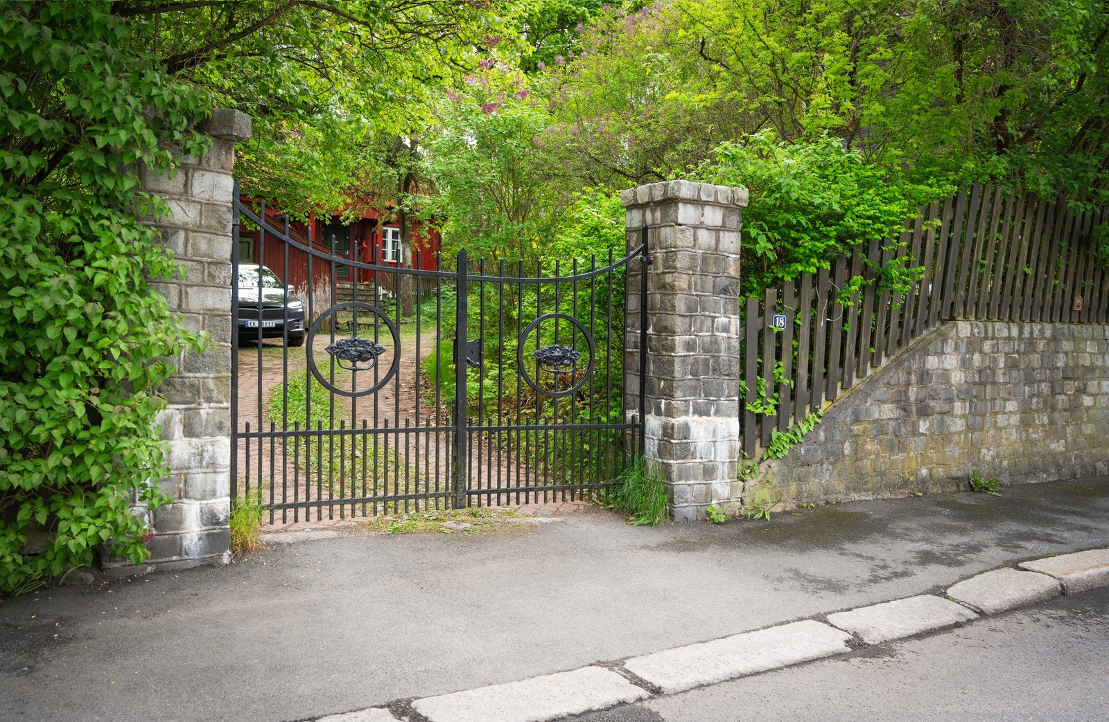 Eiendommene Huk Aveny 18 A og B deler felles innkjørsel fra gaten med smijernsport. Galleribilde
