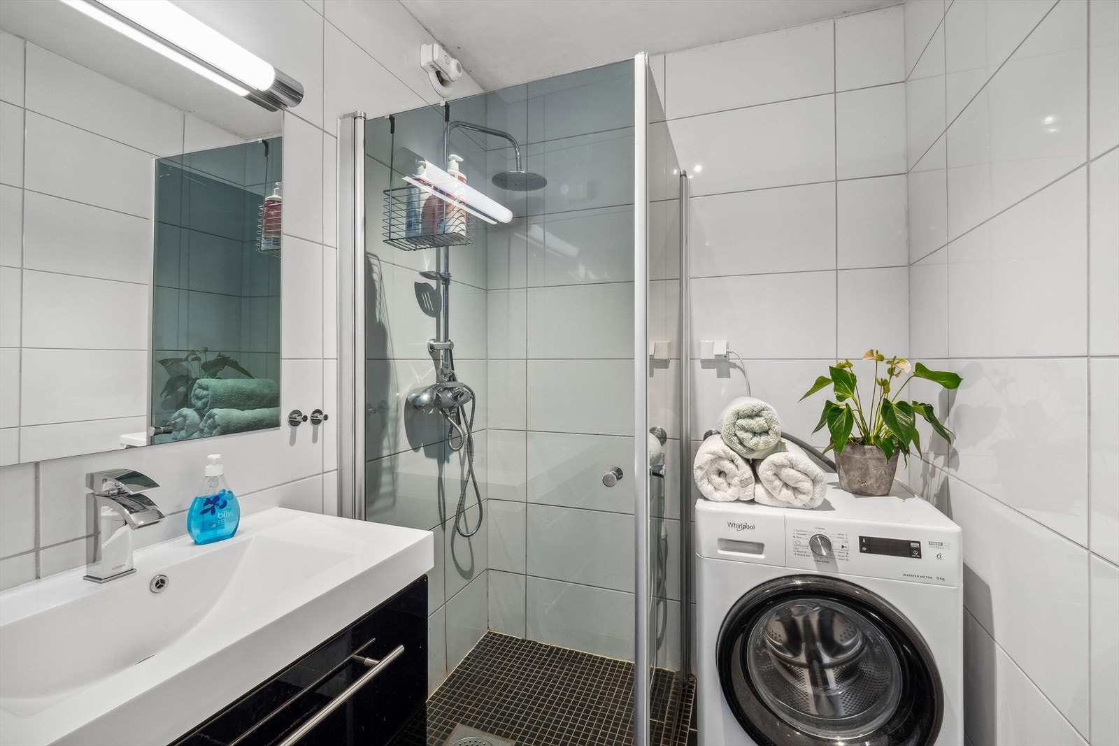 Badet har flislagte overflater og gulvvarme, med en innredning som inkluderer romslige skuffer og heldekkende servant. Galleribilde