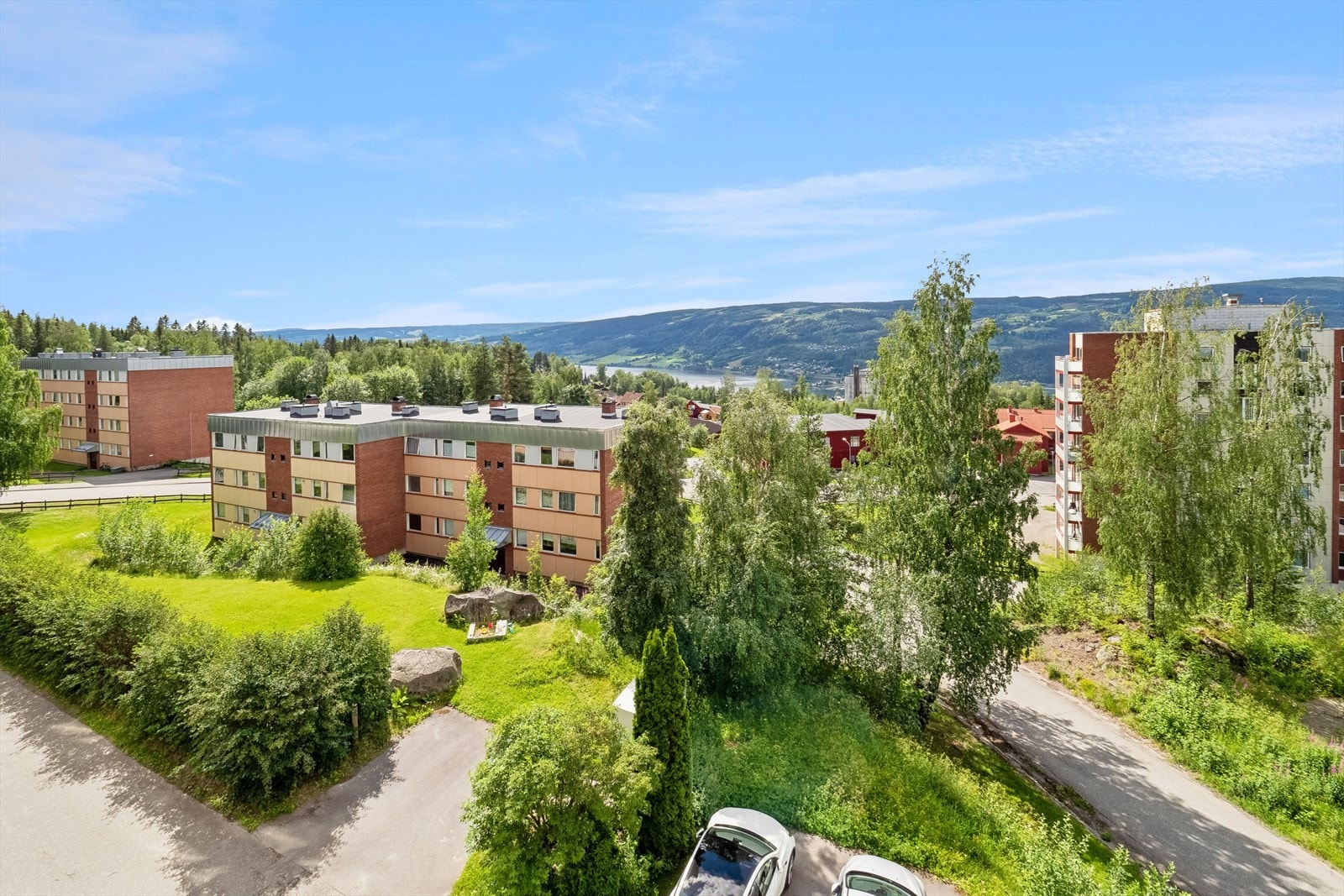 Pent opparbeidet felles tomt med plen, beplantning og asfaltert gårdsplass. Galleribilde