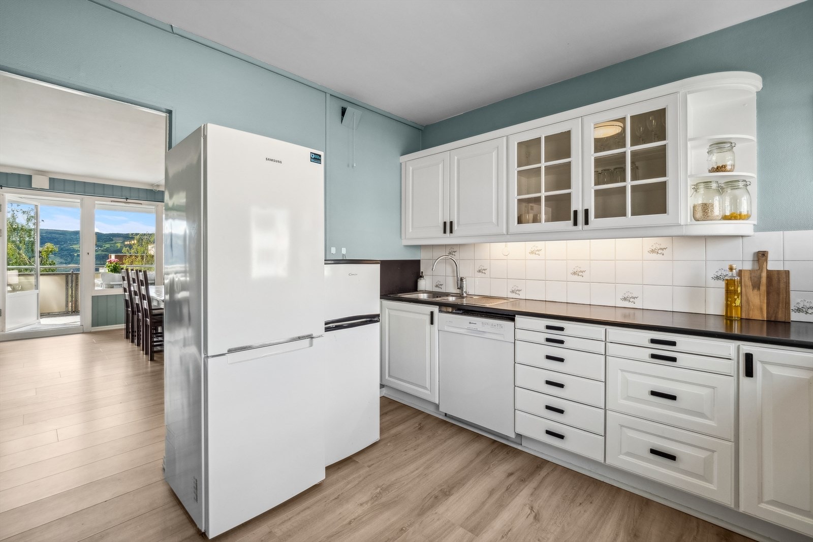 Kjøkkeninnredningen er av eldre dato med hvite, profilerte fronter og mørk laminat benkeplate. Galleribilde