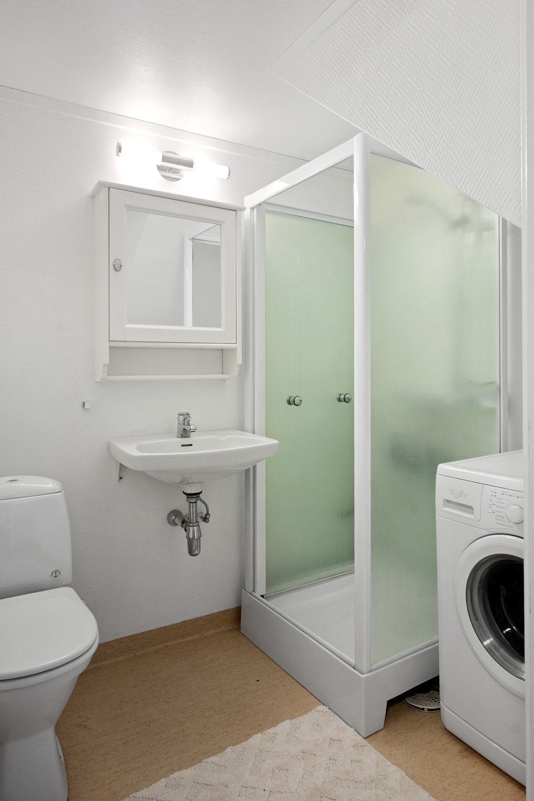 Vel inne er det tilgang til hybelens bad og trapp til 2. etasje. Badet har dusjkabinett, toalett, enkel servant, speilskap og opplegg for vaskemaskin. Galleribilde