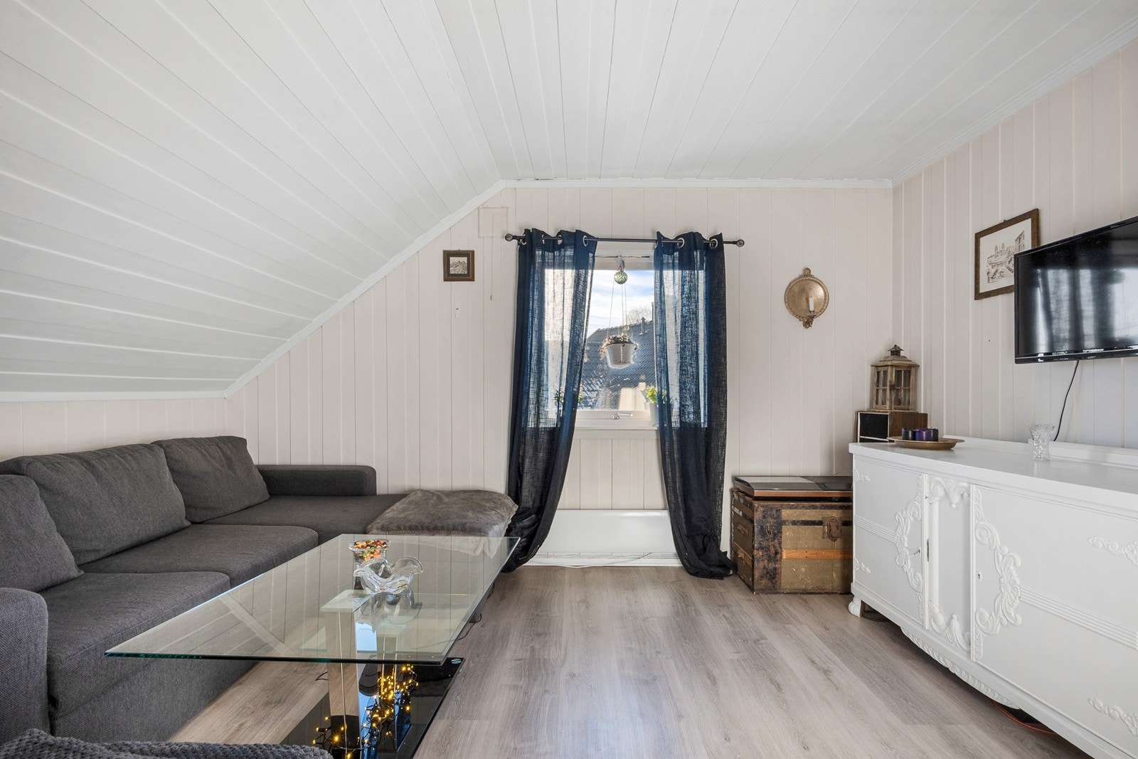 Fra hybelens entré fører trapp til 2. etasje. Stuen har lyse overflater og plass til TV- og sofaløsning. Dette er opprinnelig et godkjent soverom. Galleribilde