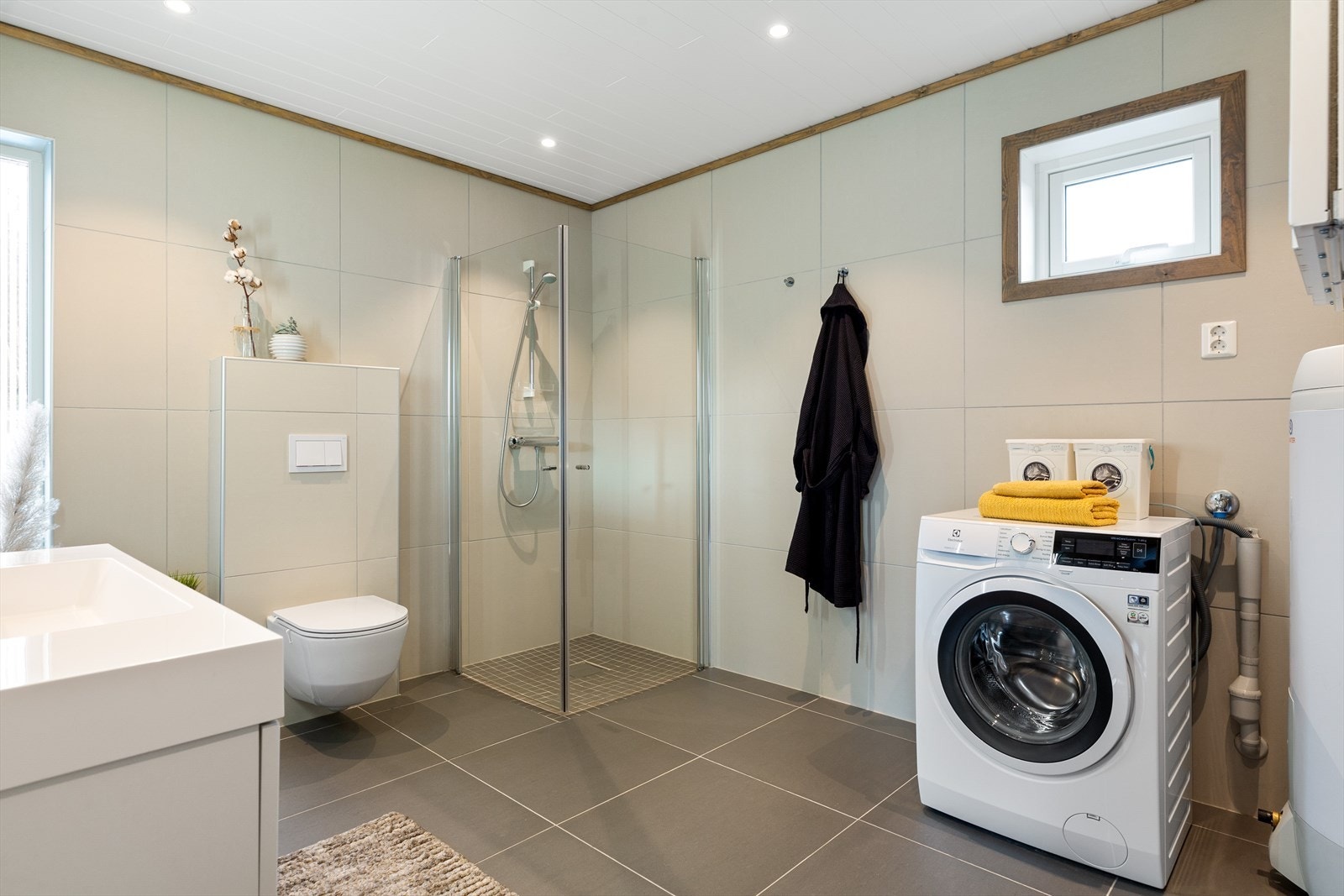 Badet er innredet med servantskap, innfellbare dusjdører, veggmontert wc og opplegg for vaskemaskin. Galleribilde