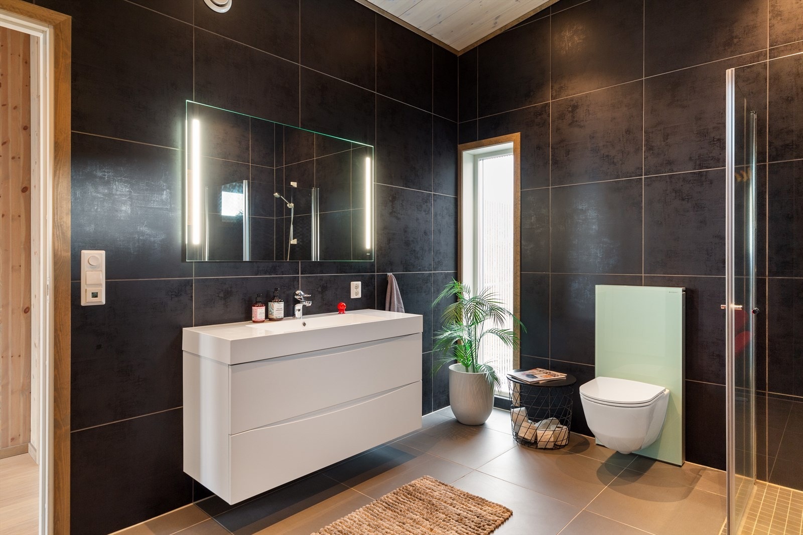 Badet er innredet med servantskap, innfellbare dusjdører og veggmontert WC for en enkel hverdag. Galleribilde