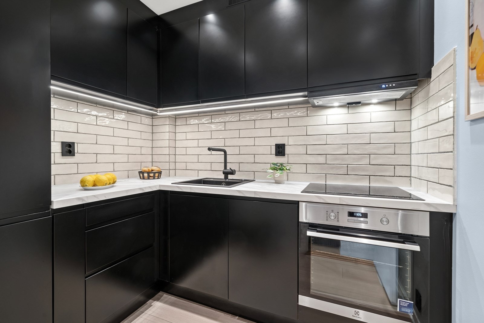 Stilrent Epoq kjøkkeninnredning fra 2022 med sorte glatte fronter, integrerte håndtak/grep og laminerte benkeplater i imitert stein. Nedfelt oppvaskkum i sort kompositt og sort ettgreps kjøkkenarmatur. Galleribilde