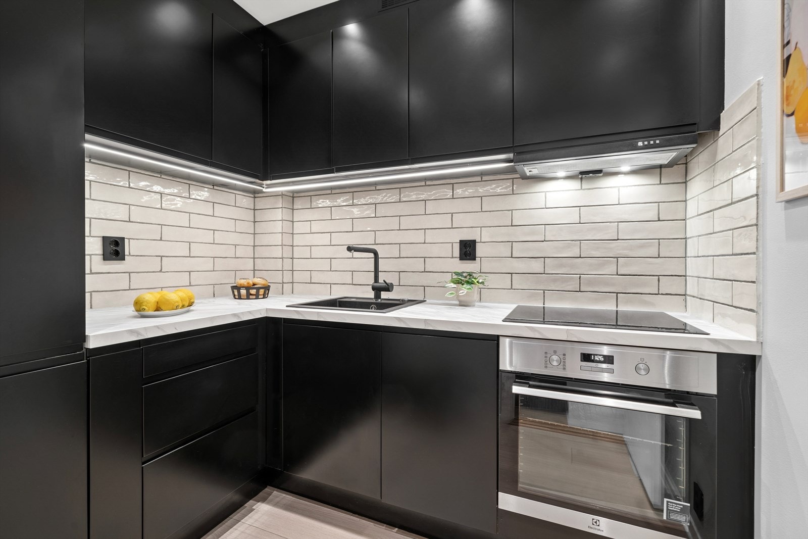 Stilrent Epoq kjøkkeninnredning fra 2022 med sorte glatte fronter, integrerte håndtak/grep og laminerte benkeplater i imitert stein. Nedfelt oppvaskkum i sort kompositt og sort ettgreps kjøkkenarmatur. Galleribilde