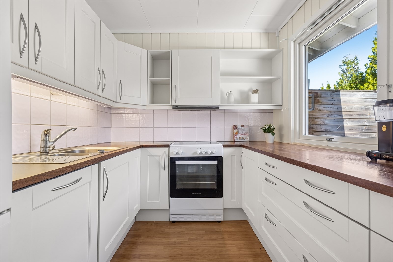 Kjøkkenet ligger i en delvis åpen løsning - praktisk skjermet fra stuen, men likevel med god kontakt til boligens sosiale sone. Galleribilde