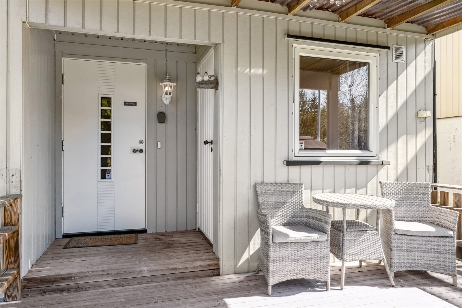 Inngangsparti og hage. Boligen har et pent inngjerdet inngangsparti med platting og takoverbygg - taket dannes av verandaen i etasjen over. Galleribilde