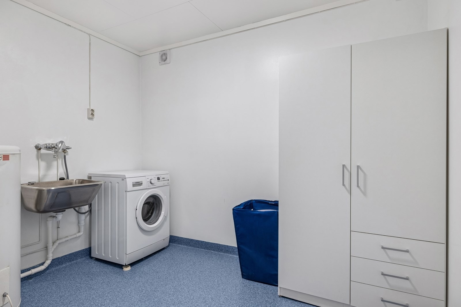 Romslig vaskerom som ligger vegg i vegg med badet i underetasjen, gir praktisk oppbevaring og god plass til vask. Galleribilde