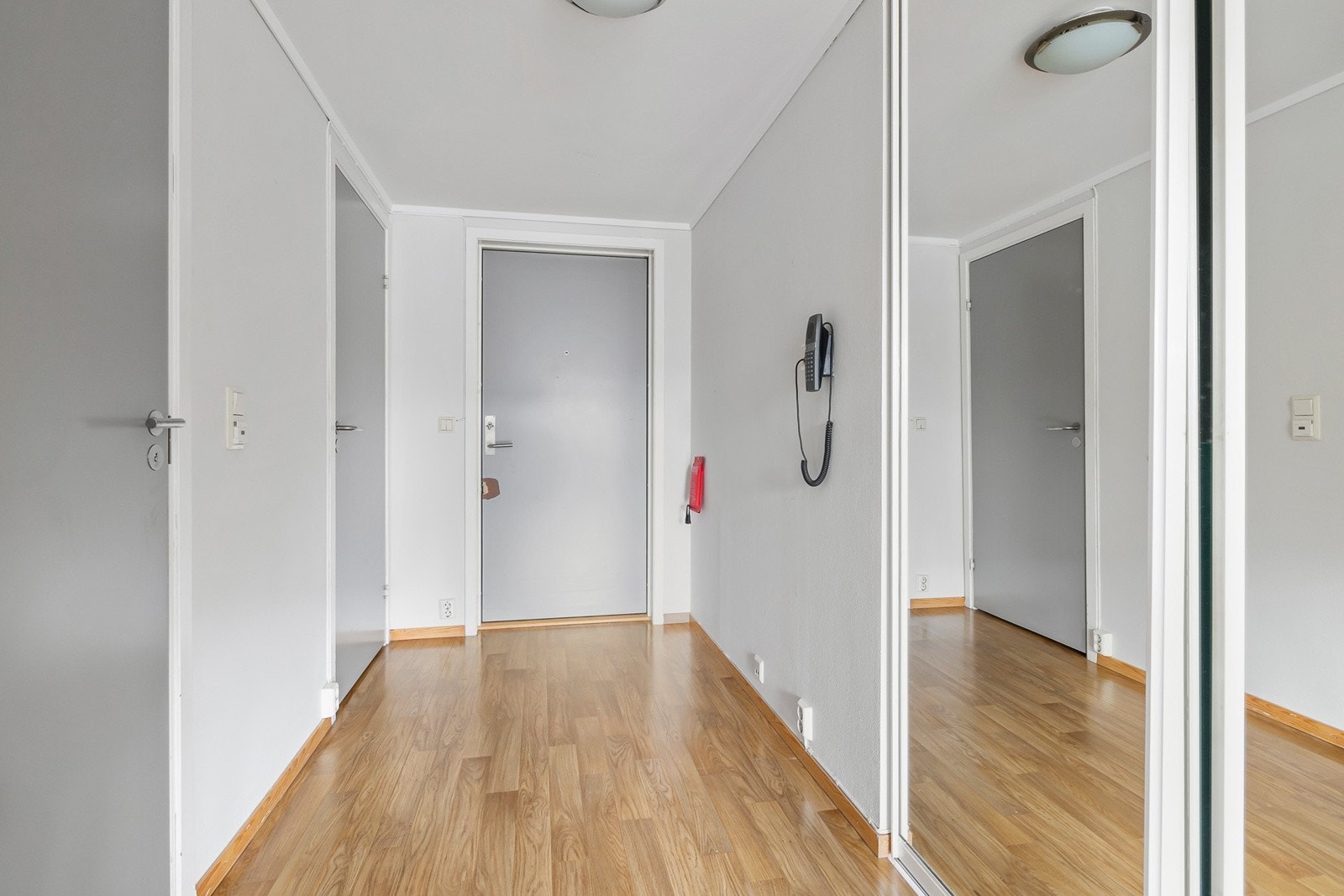 Velkommen inn! En lys gang med fin skyvedørsgarderobe med speilfronter Galleribilde