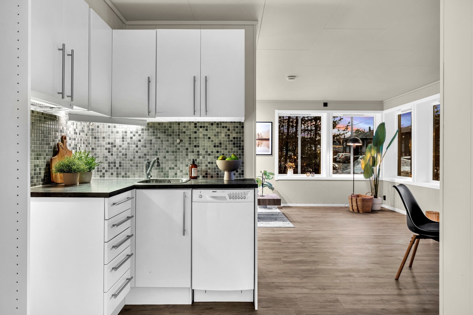 Stilrent kjøkken i åpen løsning mot stuen, fra 2007. Kjøkkeninnredning med hvite fronter og håndtak. Avsatt plass til hvitevarer. Oppvaskmaskin medfølger Galleribilde