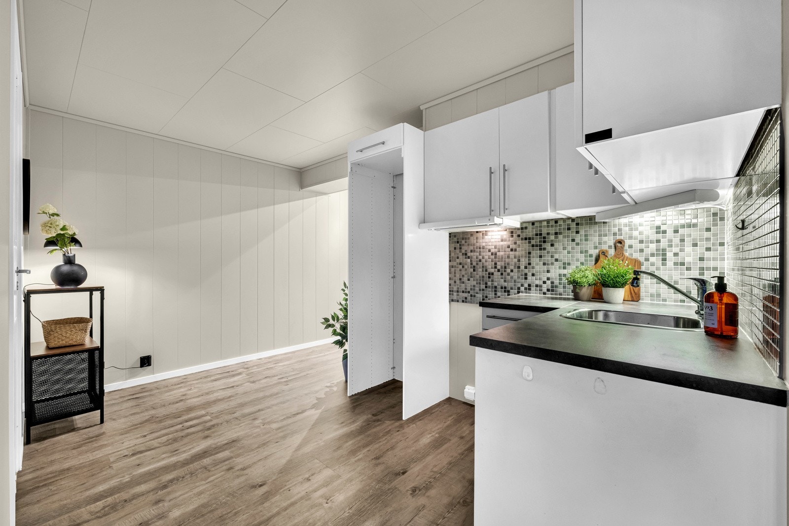 Kjøkkenet er fint plassert i midten av leiligheten. Stilrent kjøkken i åpen løsning mot stuen, fra 2007. Kjøkkeninnredning med hvite fronter og håndtak. Avsatt plass til hvitevarer. Oppvaskmaskin medfølger Galleribilde