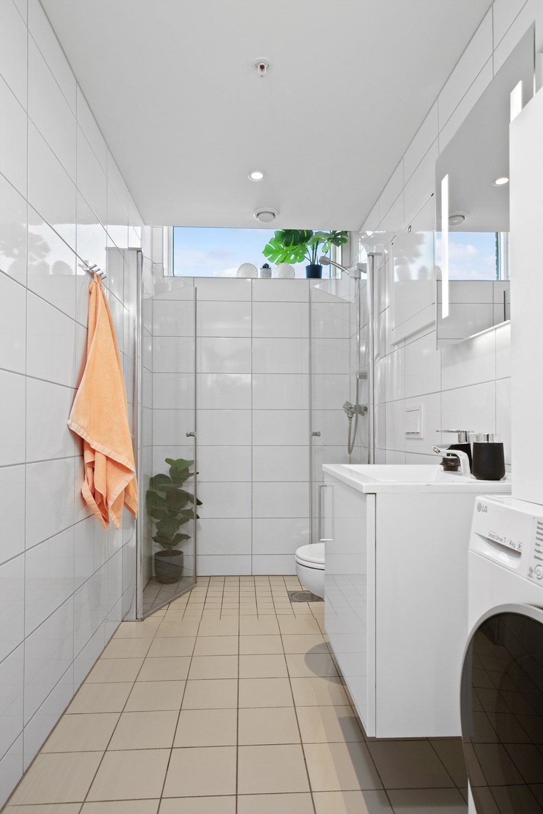 Helfliset baderom med gulvvarme og innfelte downlights i himling. Badet er utstyrt med dusjhjørne med veggmontert dusjdør og blandebatteri, innredning med nedfelt servant, speil over vask og TECE veggmontert klosett. Galleribilde