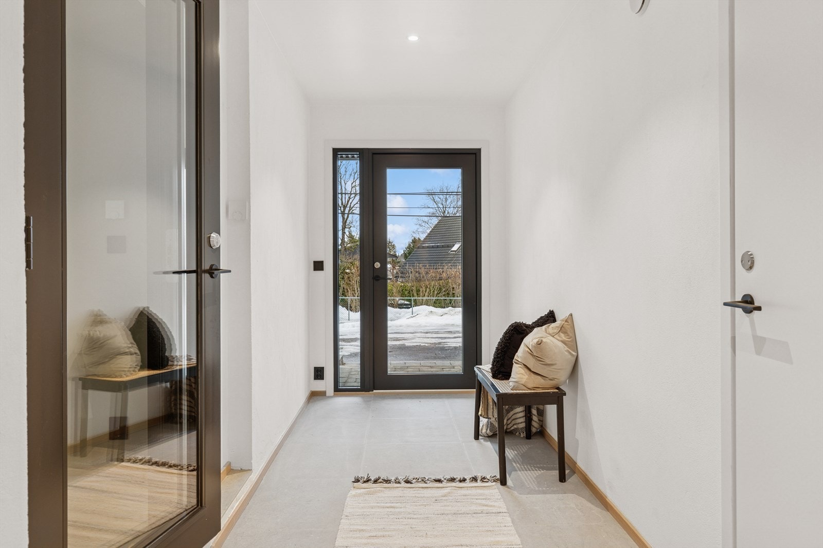 Velkommen inn! Dør til garasjen til høyre og hallen til venstre. Lys grå fliser på gulv, glatte, malte flater og downlights i himlingen. Galleribilde