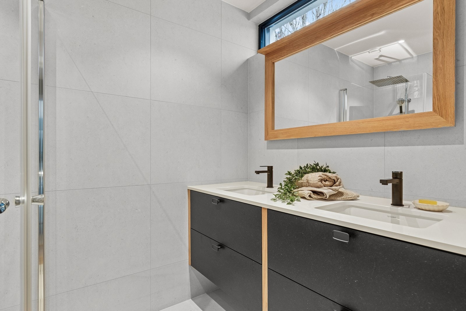 Baderommet er av samme kvalitet som hovedbadet, med dobbelservant, fronter i sort valchromat og eik skuffer med fingerskjøter på hjørnene. Speilramme av solid eik med lys. Galleribilde