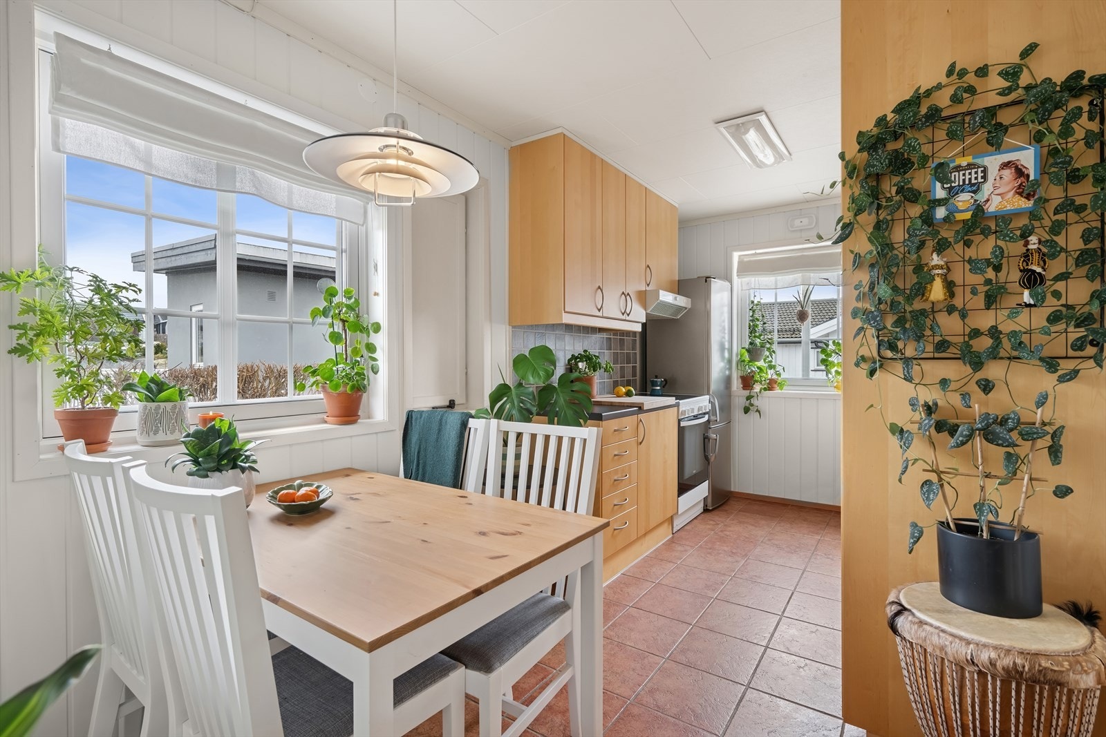 Kjøkkeninnredning med glatte fronter og laminert benkeplate med fliser på vegg over benkeplaten. Galleribilde