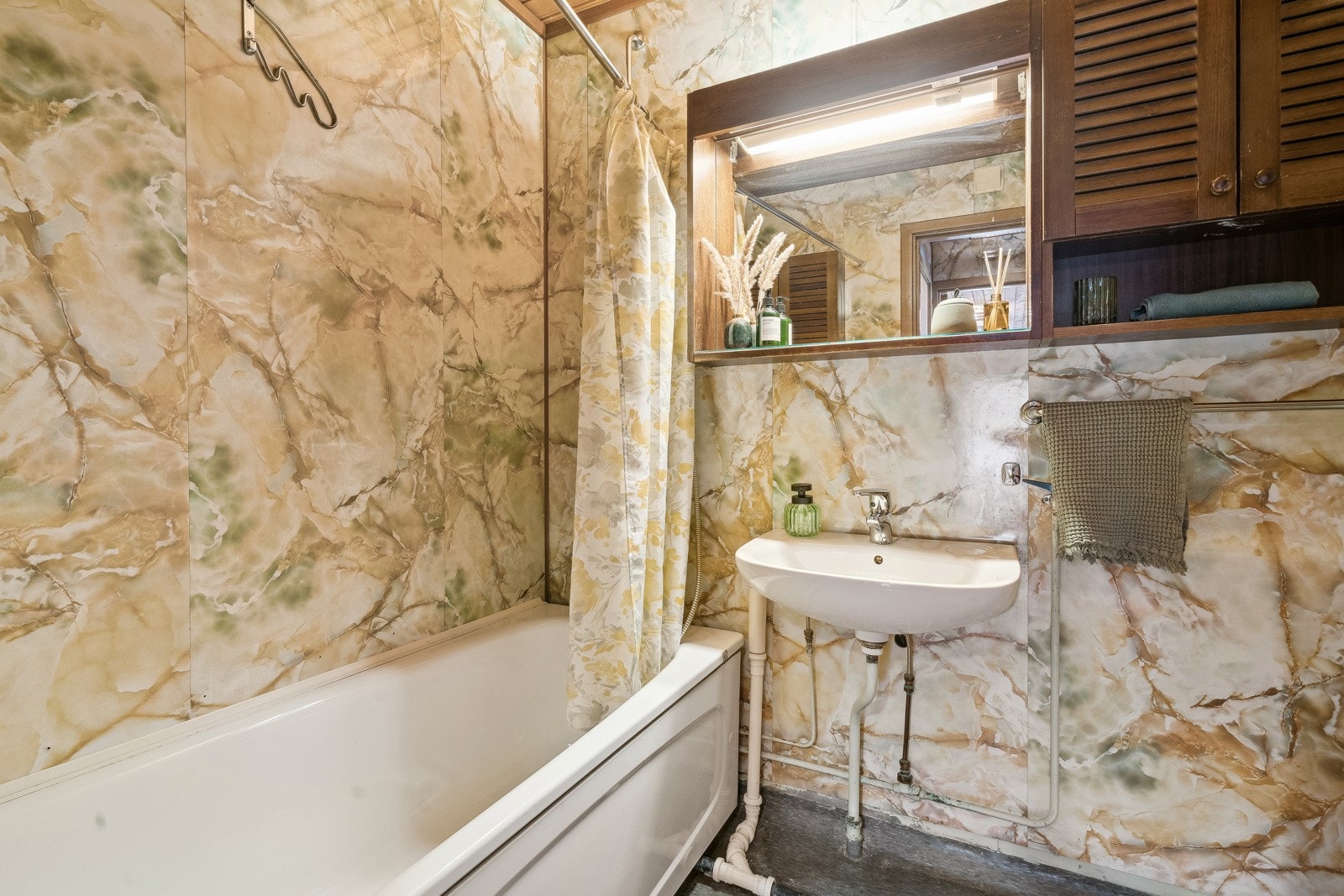 Romslig og funksjonelt baderom fra byggeåret med god plass og praktiske løsninger. Gulvet er belagt med slitesterkt gulvbelegg, mens veggene har baderomsplater og himlingen er kledd med panel. Opplegg til vaskemaskin. Galleribilde
