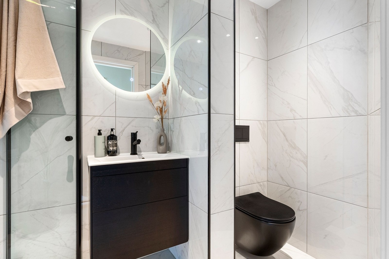 Det inneholder dusjvegger av glass og dusjgarnityr på vegg, vegghengt toalett, innredning med servant, opplegg for vaskemaskin (kran og avløp). Galleribilde