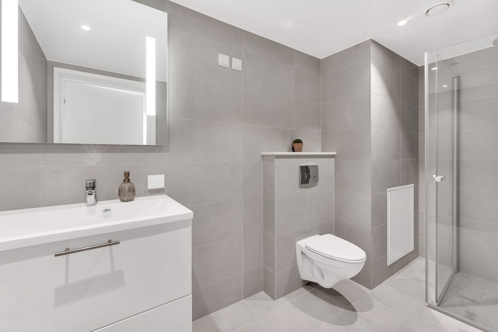 Stilrent og flislagt bad med elektriske varmekabler og opplegg for vaskemaskin. Galleribilde