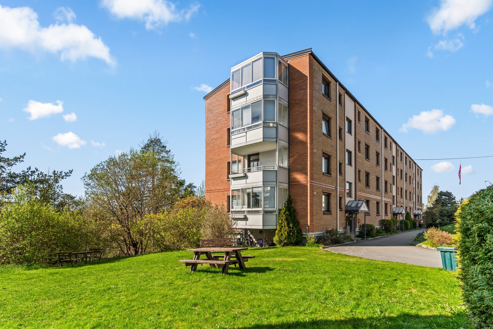 Rundt og mellom bebyggelsen er det et sosialt fellesområde med plen, sittegrupper, grillplass og flere lekeapparater. Galleribilde