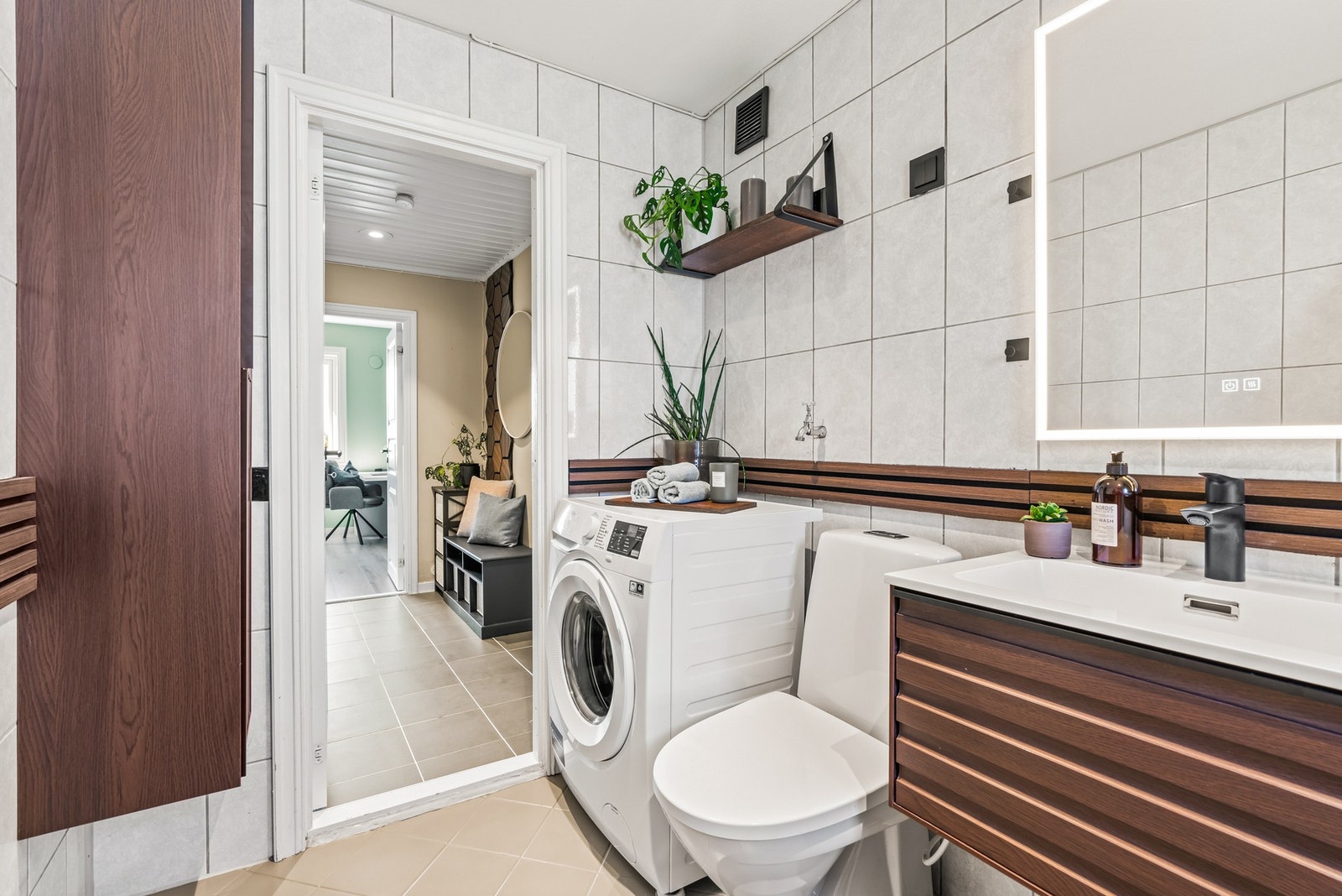 Moderne innredning med mørke fronter, heldekkende servant og speil med integrert lys. Galleribilde