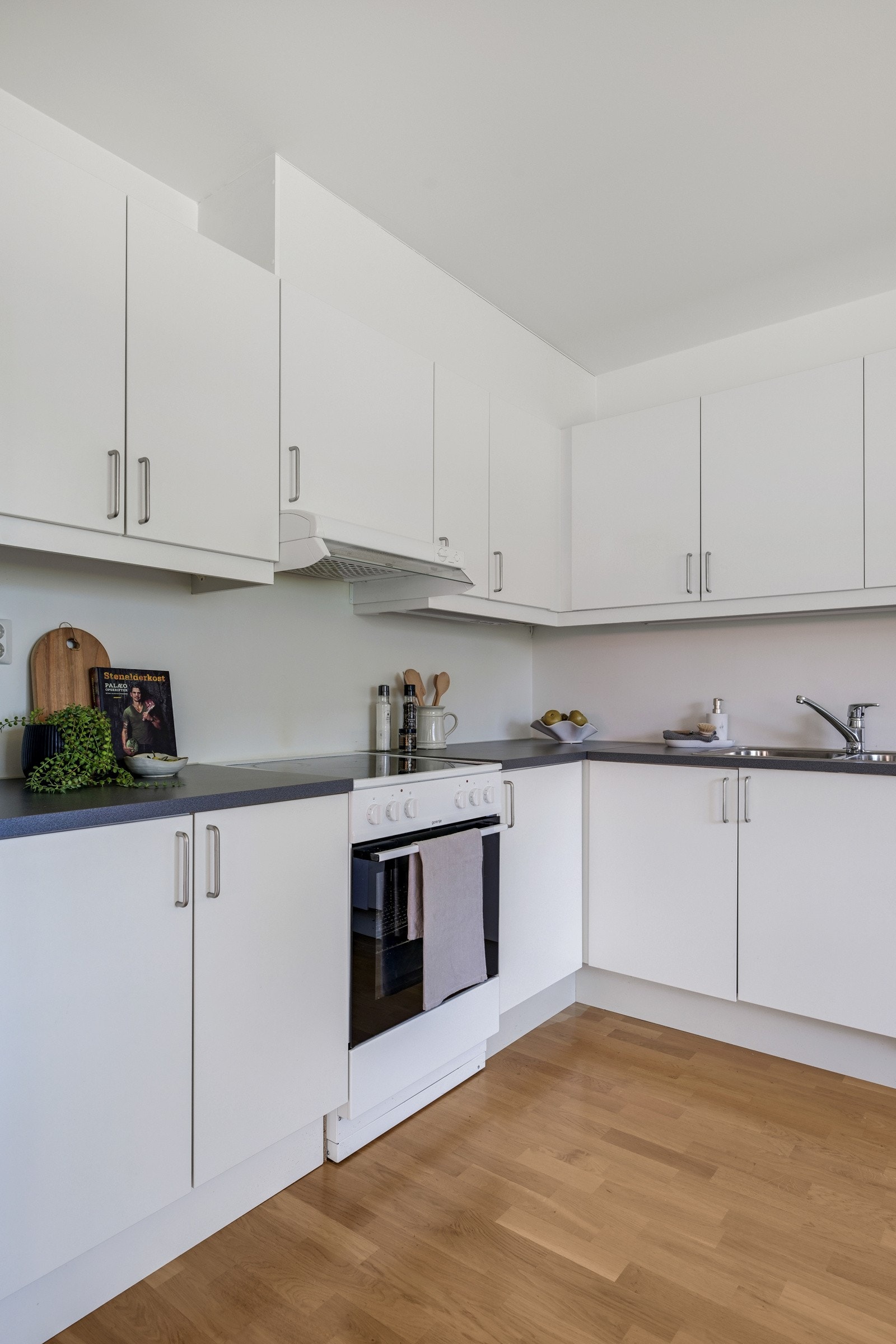 Pent og vedlikeholdt kjøkken fra byggeår med malte fronter og parkett på gulv Galleribilde