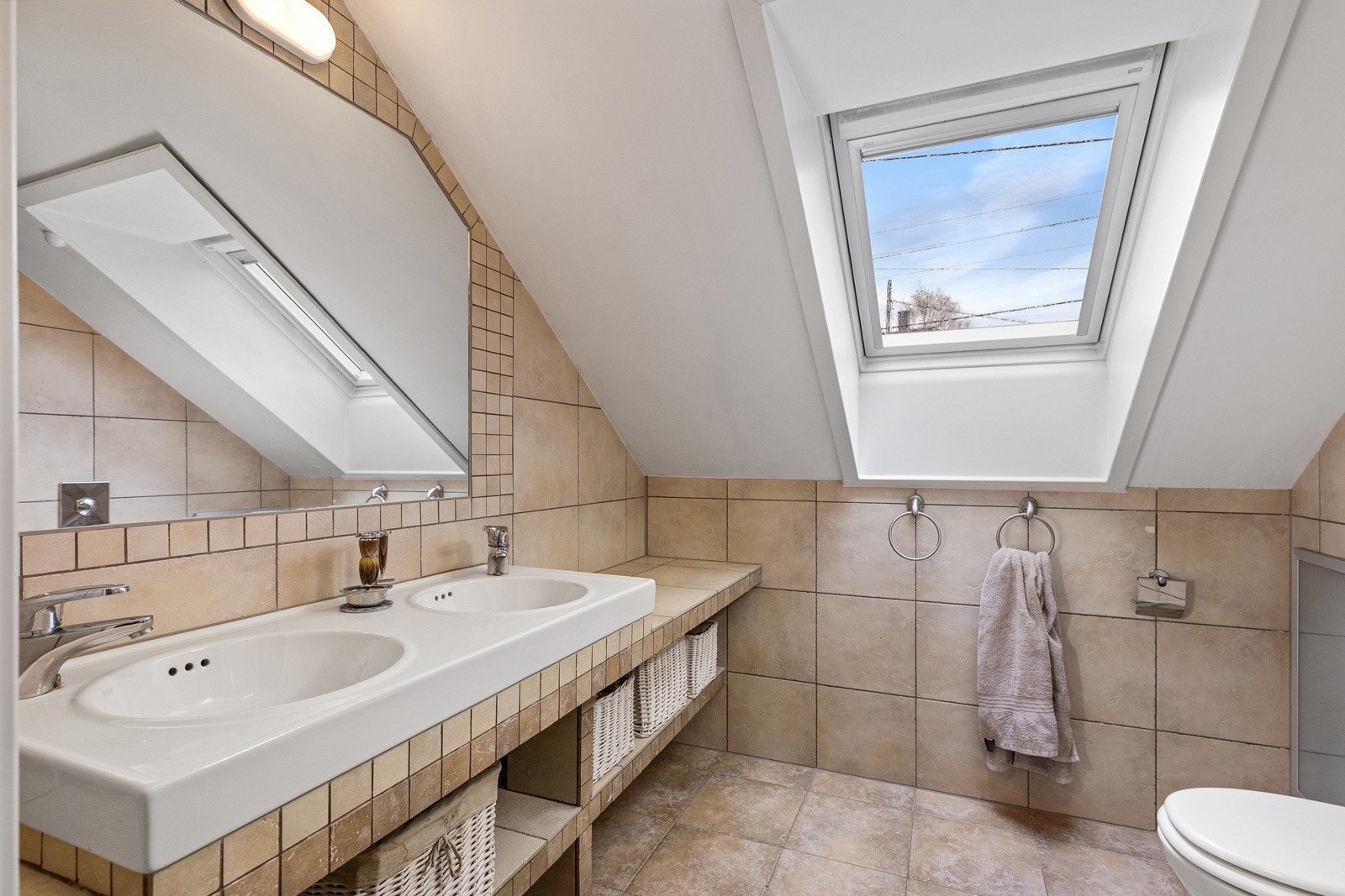 Moderne bad fra 2012. Flislagte gulv med varmekabler og flislagte vegger. Badet har dobbel servant med plassbygget benk og hyller, speil med belysning, vegghengt toalett og dusj med herdet glassdører. Galleribilde