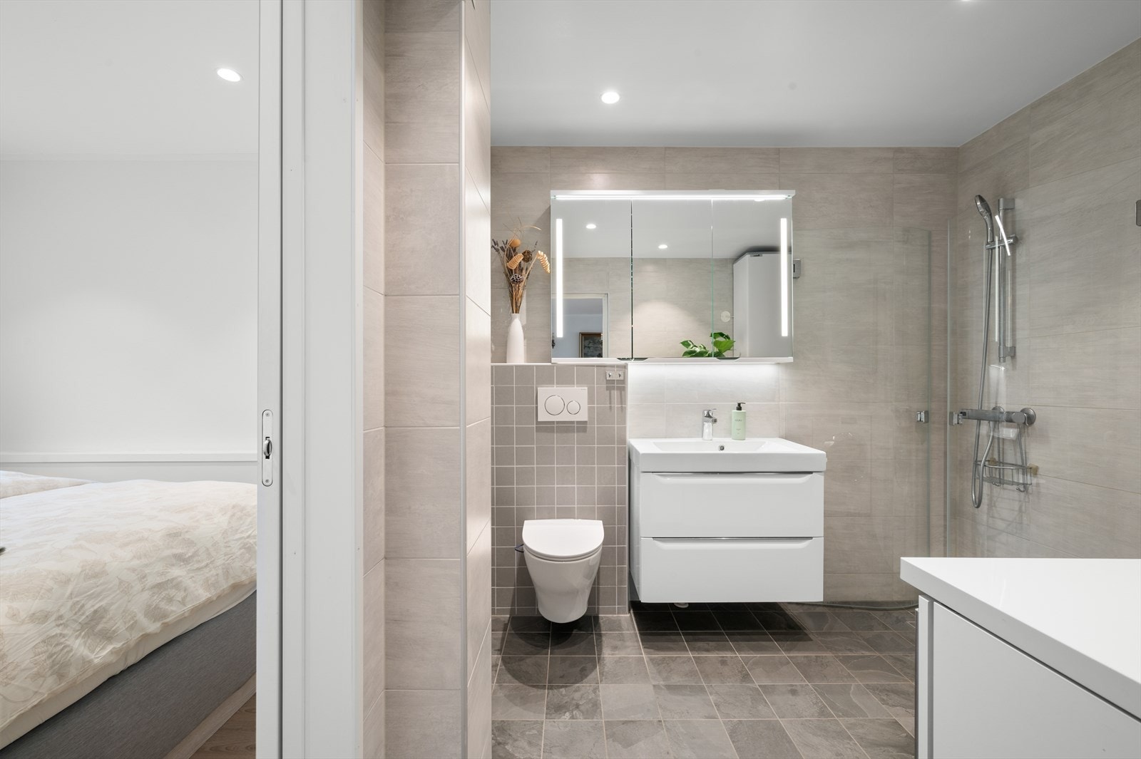 Badet ble, i likhet med resten av leiligheten, oppgradert i 2017 og fremstår som moderne og funksjonelt. Det er innredet med vegghengt toalett, helstøpt servant med skuffer i stilrene, slette fronter, dusjdører i klart glass og opplegg for vaskemaskin. Galleribilde