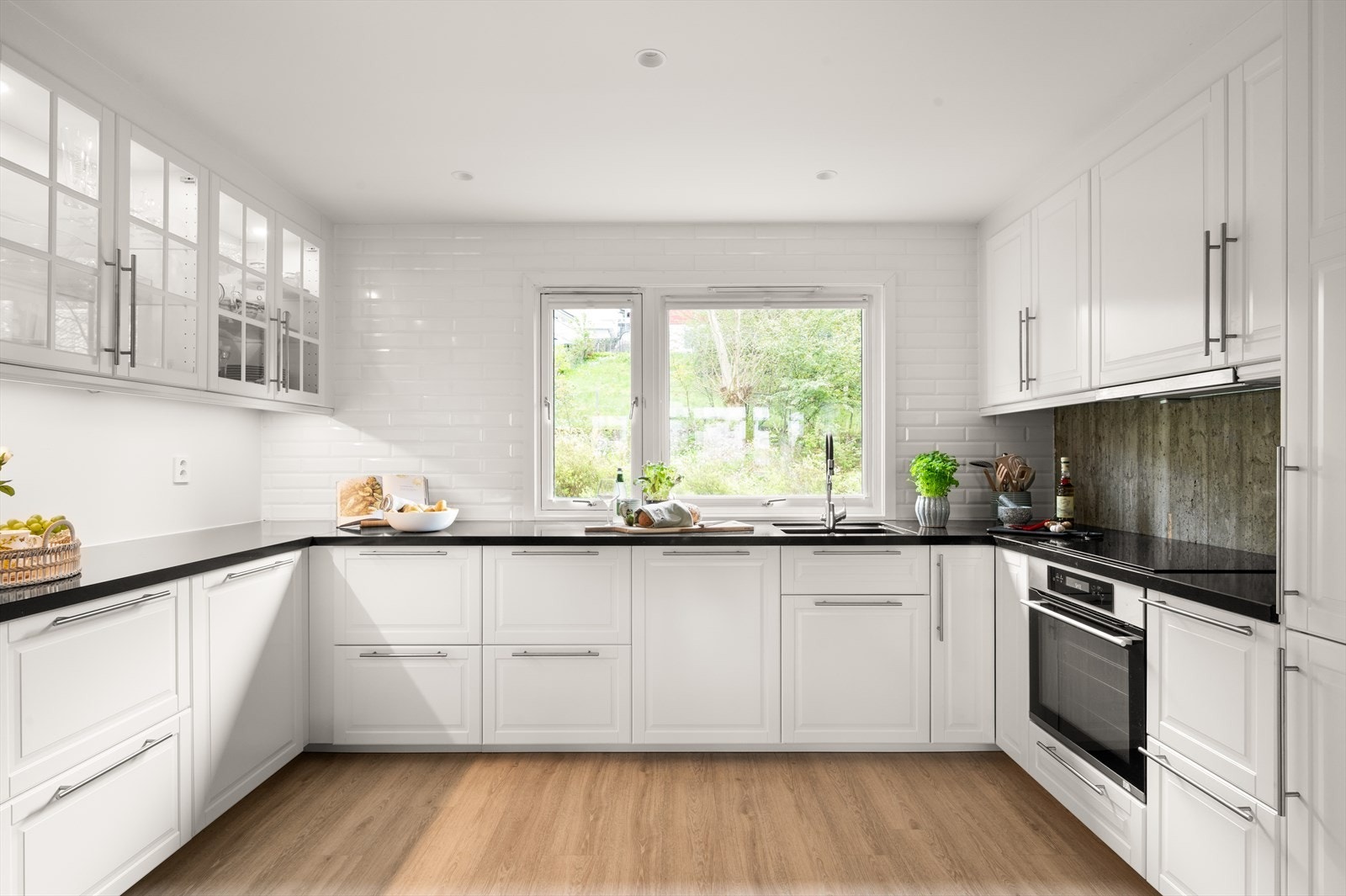 Kjøkkenet fremstår stilrent og gjennomført, med profilerte fronter som gir et klassisk uttrykk, kombinert med benkeplate i stein og moderne fliser med betongpreg over benk - en harmonisk blanding av eleganse og industriell karakter. Galleribilde