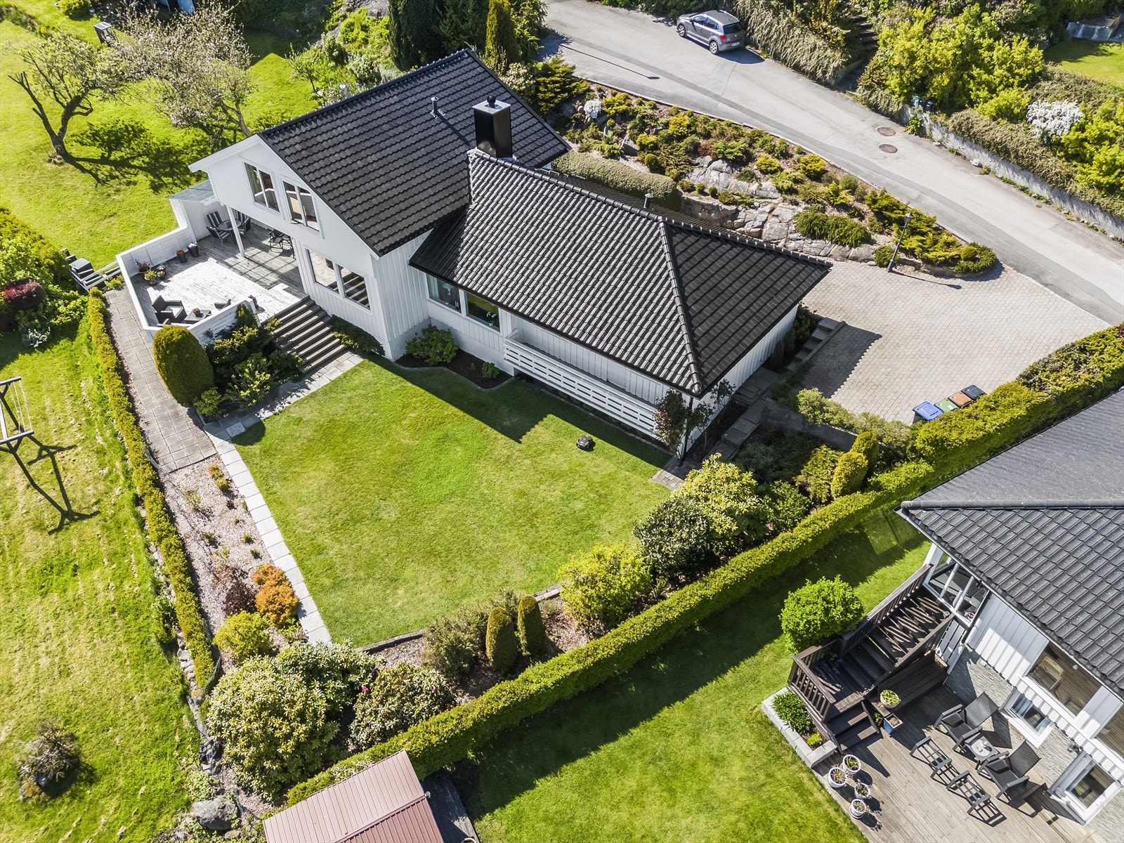 Tomten er meget pent opparbeidet med flat plenlagt område, beplantning og steinlagt tun. Galleribilde