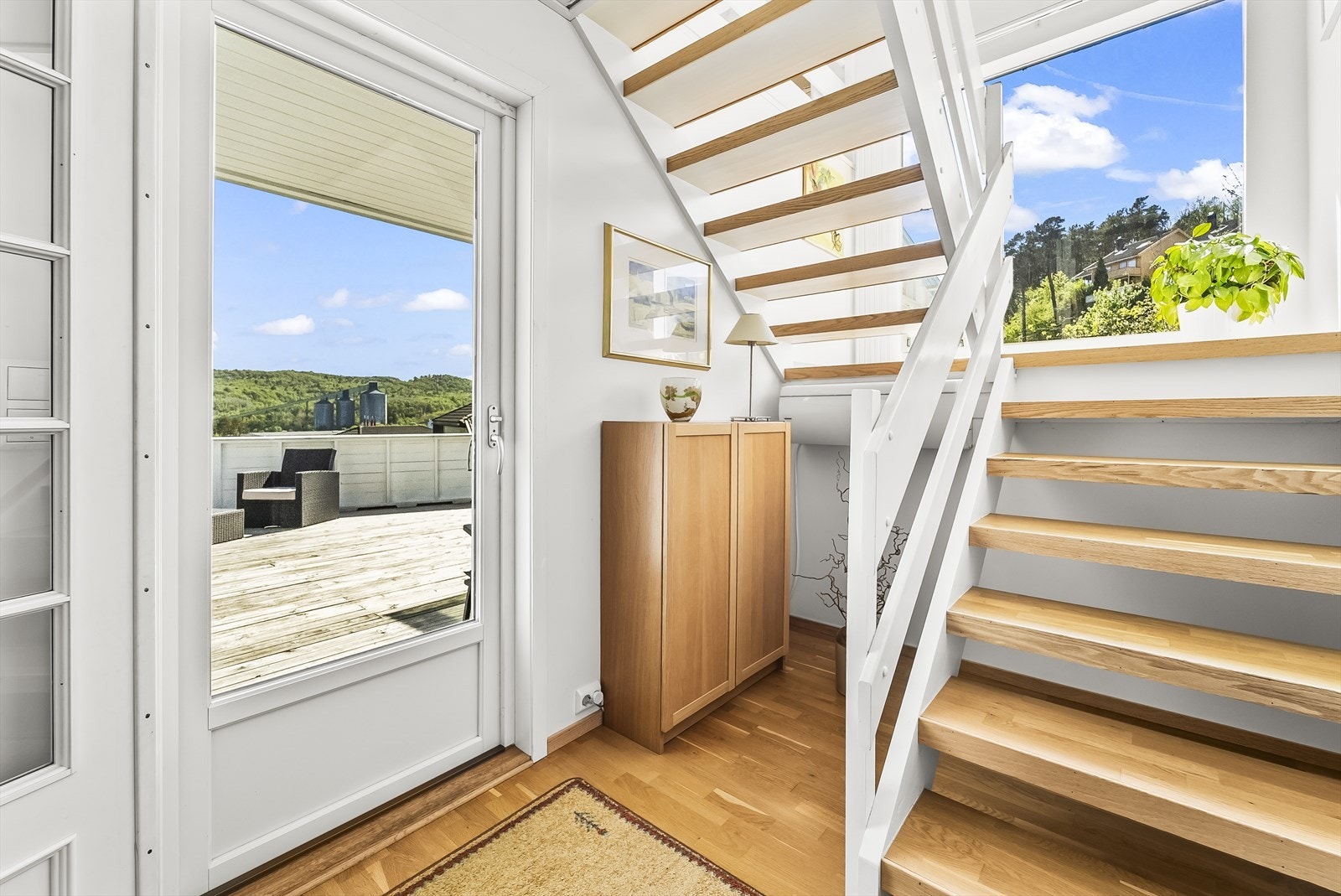 Utgang til en solrik terrasse og trappesats opp til loftet. Varmepumpe under trapp. Galleribilde