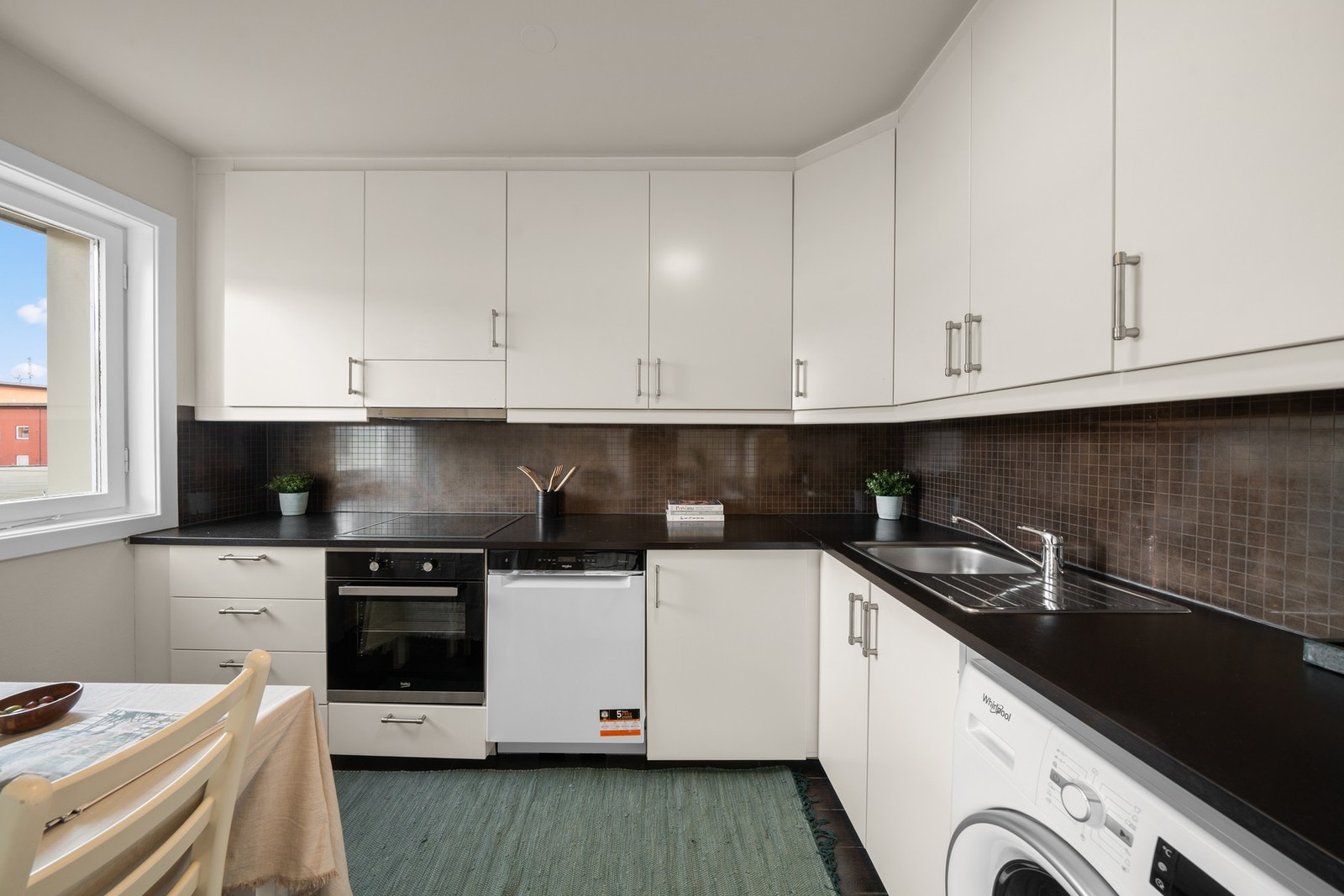 Innredningen består av glatte, hvite fronter og en mørk laminatbenkeplate som gir en stilig kontrast. Galleribilde