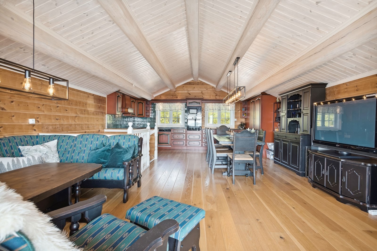 I hyttas 2. etasje har du et stort allrom med kjøkken og utgang til balkong. God standard fra 2007 med pen enstavs parkett på gulv med gulvvarme, overflater med panel og mønet himling med panel og synlige rundstokker. Galleribilde