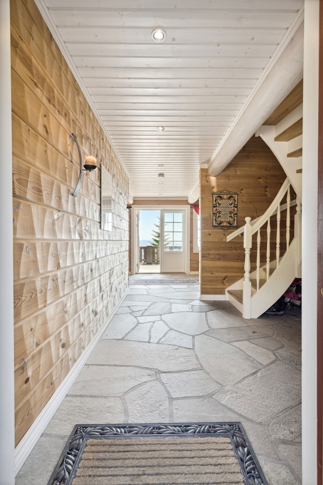 Videre kommer du inn i en romslig hall som fungerer som et fint knutepunkt i hytta. Hallen er utstyrt med en eldre koksovn og garderobeskap for oppbevaring. Fra hallen har du også doble dører ut til terrassen. Galleribilde