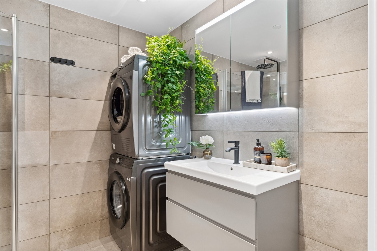 Baderommet har dusjvegger av glass, vegghengt toalett, innredning med servant samt opplegg for vaskemaskin. Overflatene fremstår som nye og ubrukt. TG0. Galleribilde