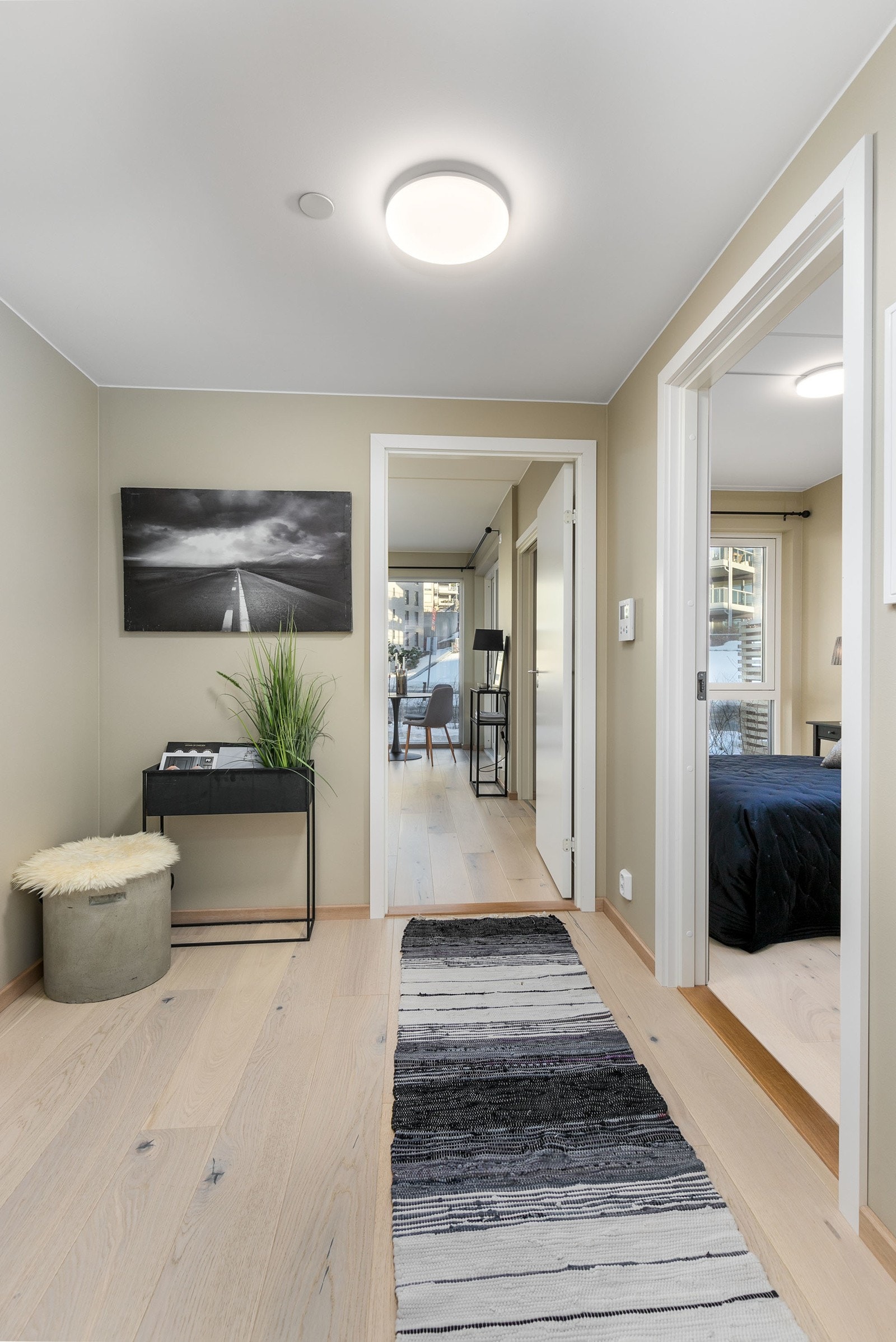 Tiltalende entre/gang med lekker hvitpigmentert parkett på gulv og lysmalte veggflater som gir et godt førsteinntrykk av leiligheten Galleribilde