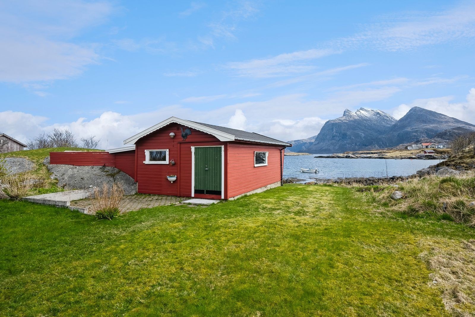 Uthuset ligger enda litt nærmere havet med utsikt mot Dønnamannen. Det er laget sløyebenk på baksiden for å kunne klargjøre middagen man nettopp har dratt opp fra havet. Galleribilde