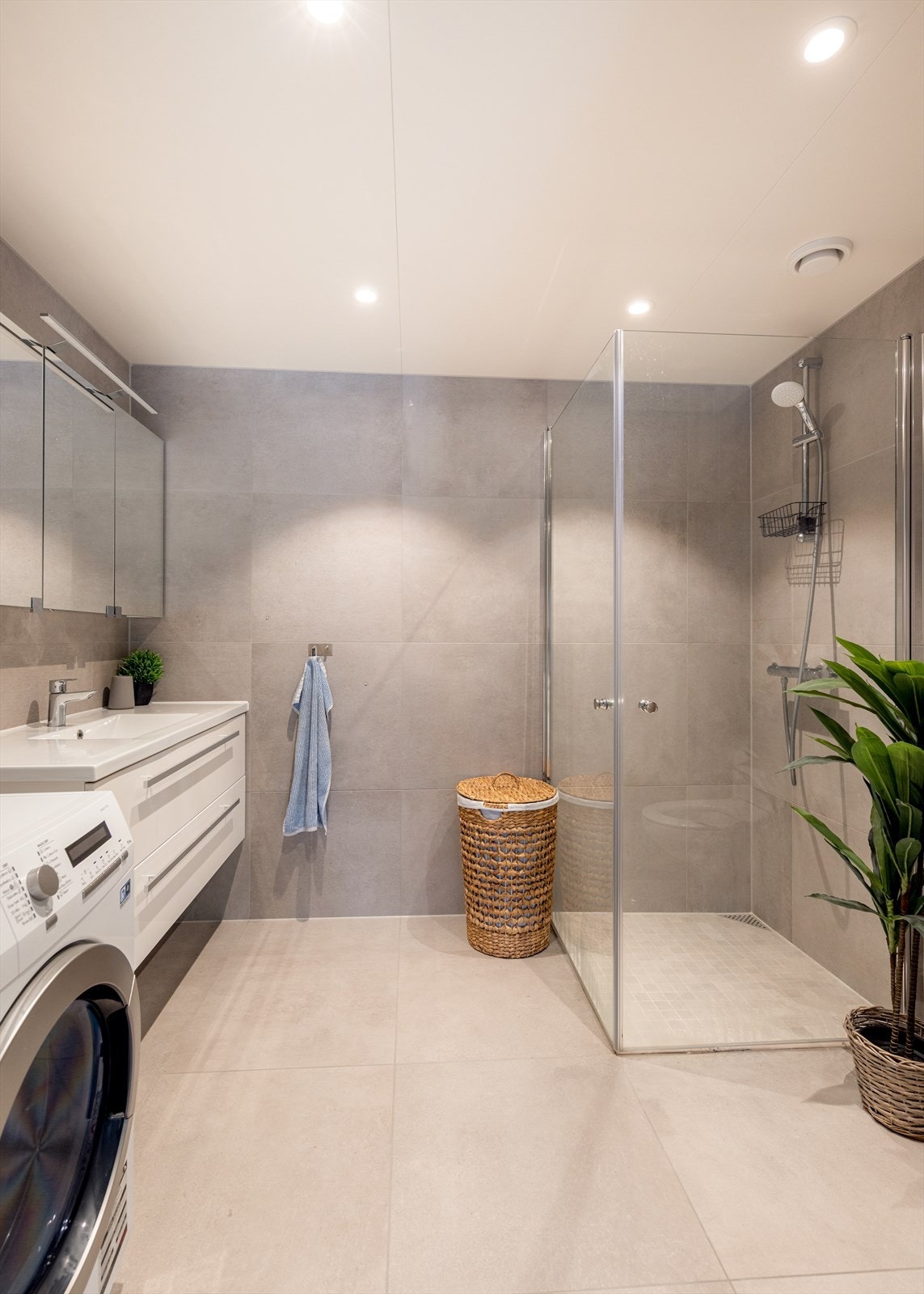 Badet tilliggende soverommet er boligens største bad, hvor det også er opplegg til vaskemaskin. Rommet har gulv av betong med varmekabler og flis på overflater, flis på vegger og hvitmalte plater i himling med integrerte downlights. Galleribilde