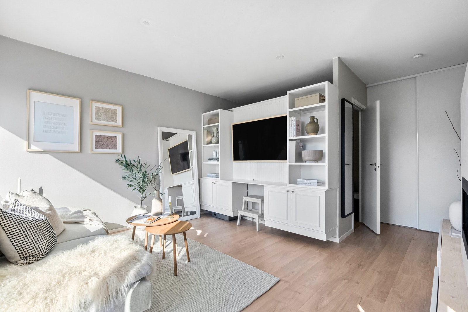 Stuen har moderne laminatgulv og malte vegger, samt en praktisk skyvedørsgarderobe som gir god oppbevaringsplass uten å ta opp gulvplass. Galleribilde