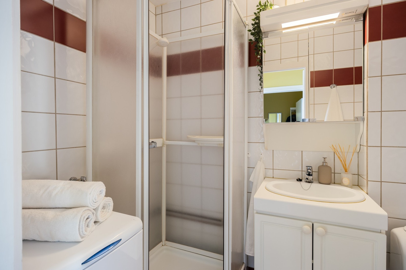 Flislagt baderom med dusjkabinett, opplegg for vaskemaskin, servant med underskap og toalett. Anbefalt oppgradering mht. alder. Galleribilde